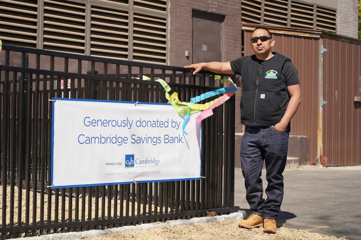 Experienced fence contractor standing beside newly installed metal fence in Auburndale, MA
