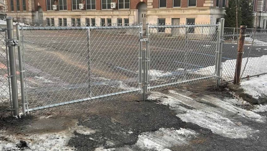 Chain link fence installation without concrete showing metal posts and gate setup on residential property
