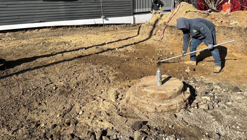 Workers preparing backyard ground for fence installation during the best time of year to install a fence at a residential property.