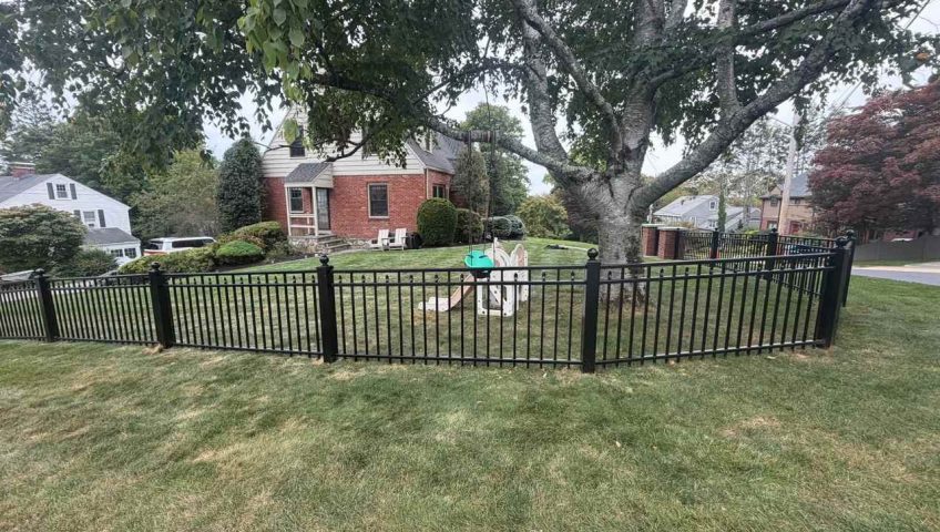 Maintained grass and landscaping along a black aluminum fence in Peabody MA